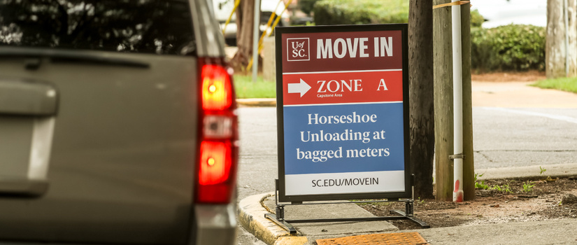 Tail lights of a car as it passes a Move-In sign highlighting parking at the Horseshoe