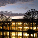 傍晚时分，托马斯·库珀图书馆正面的景色，从倒影池的对面拍摄。图书馆窗户上的灯光反射在水面上。