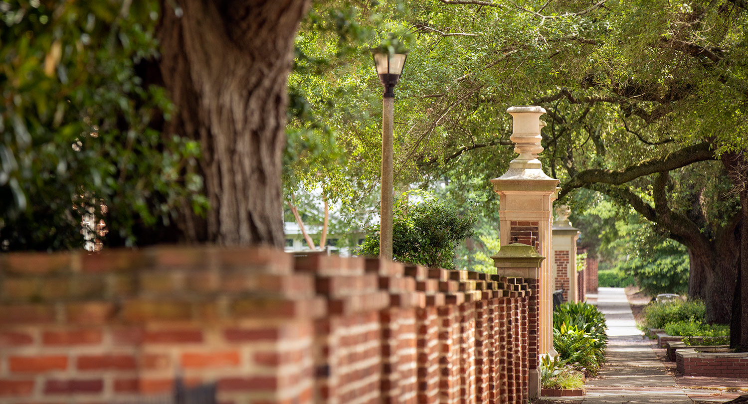 The brick wall surrounding the historic horseshoe with posts at the gates. 