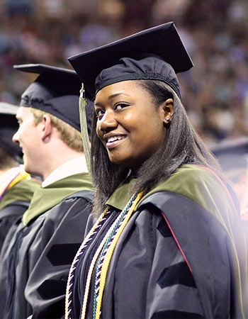 Student wearing a doctoral hood and honors cords at a commencement ceremony.
