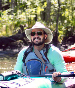 Jay Grant wears outdoor gear and paddles a river in a kayak.