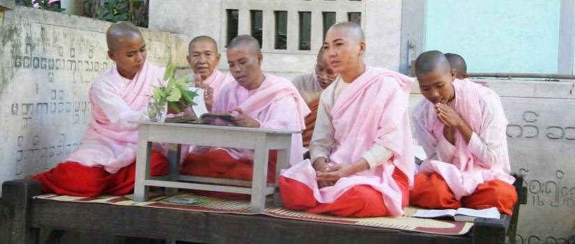 people wearing pink and red robes sharing a book