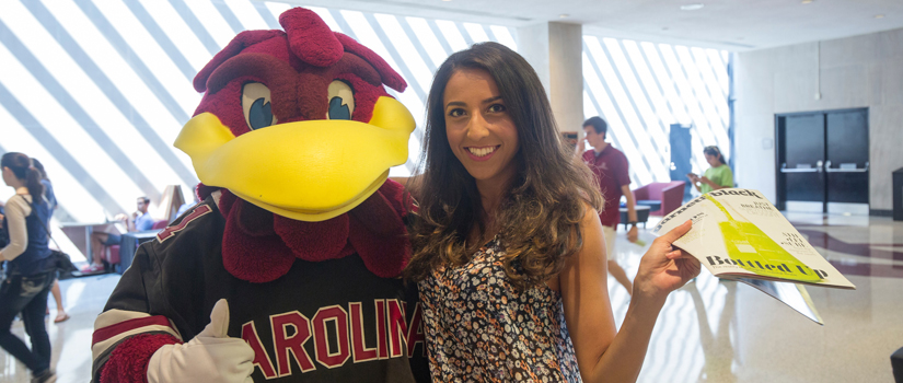 A student poses with the Gamecocks mascot, Cocky.