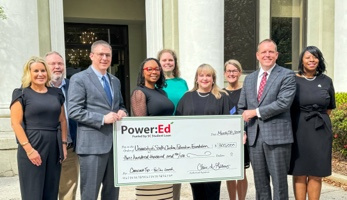 A group of people standing in front of Wardlaw College holding an oversized check 