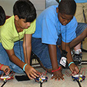 two students prepare to race robotic cars