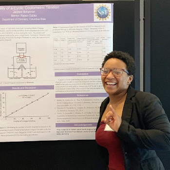 a Black woman stands by her research poster
