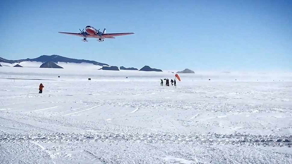 An airplane takes off in Antarctica as people watch below