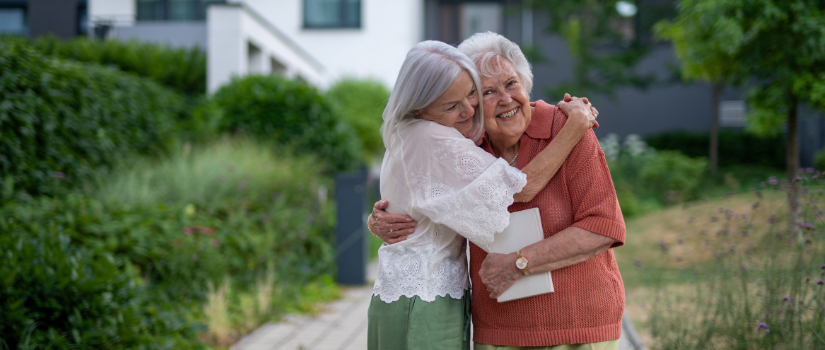 two older ladies hugging outside