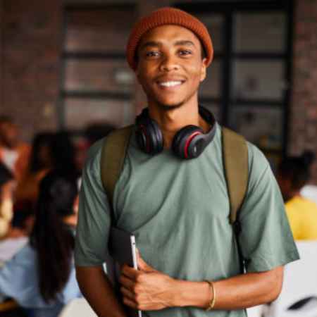 image of make student with a laptop under arm and headphones around neck