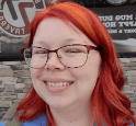 Jessica's face is pictured. She has orange hair, is wearing glasses, and is smiling. 