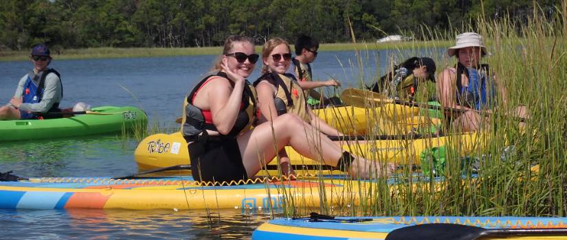 Students relaxing while on a stand up paddle board trip.