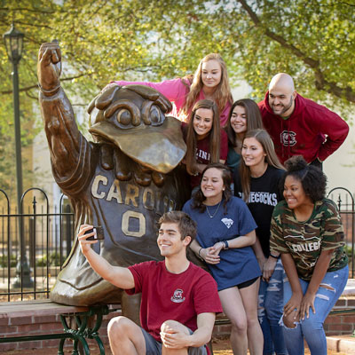 Smiling students surround the Cocky statue to take a picture.
