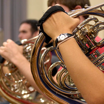 Students playing french horns in a line.