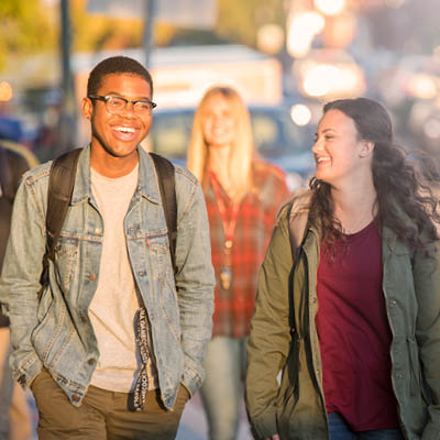 Two students walking a smiling together outdoors.
