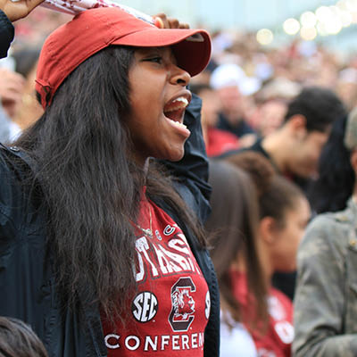 A close up of a student cheering at a sporting event.