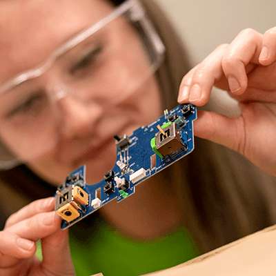 Close-up of a student holding a circuit board.