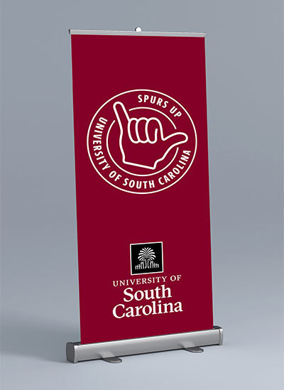 Pop up banner with the USC stamp with text spurs up and the University of South Carolina logo on a garnet background.