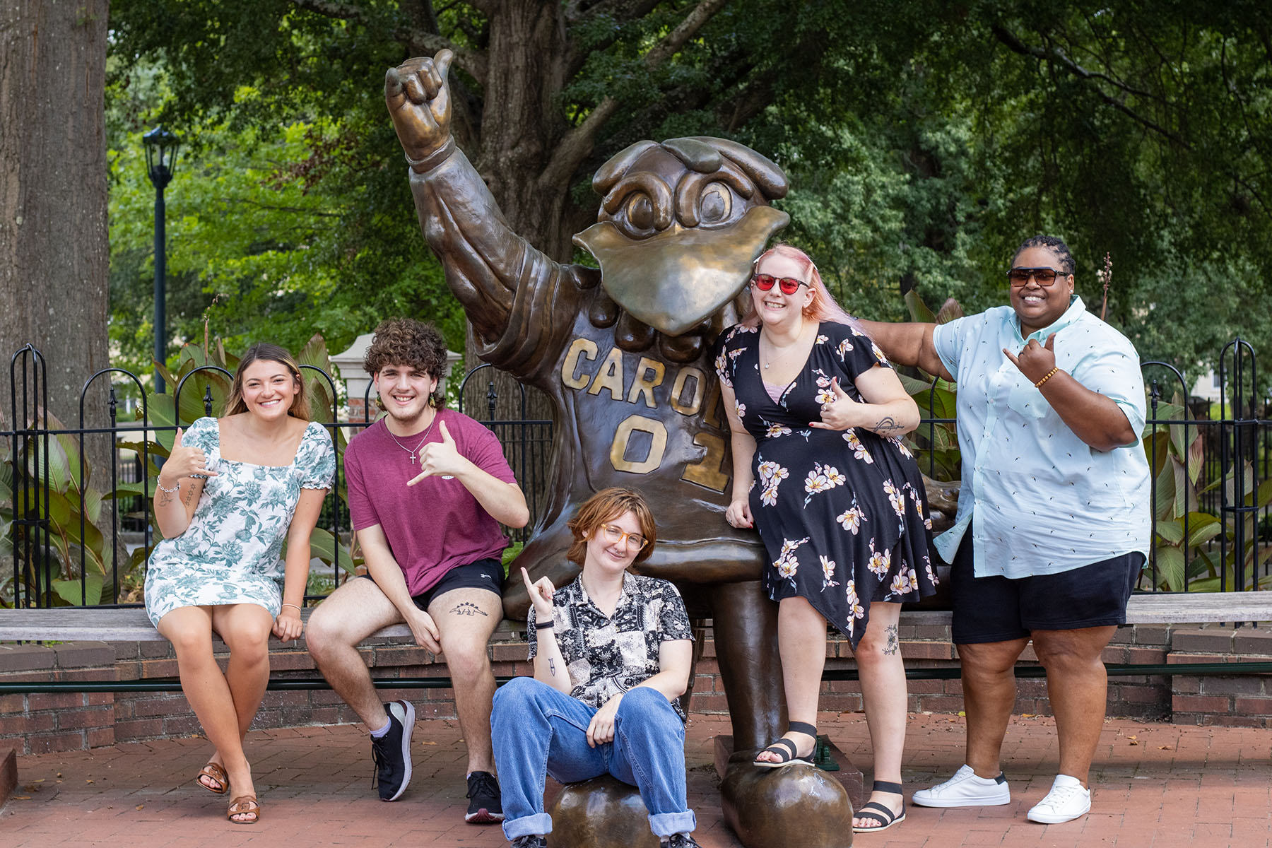 A group of students with diverse disabilities have "spurs up" with the bronze cocky statue.