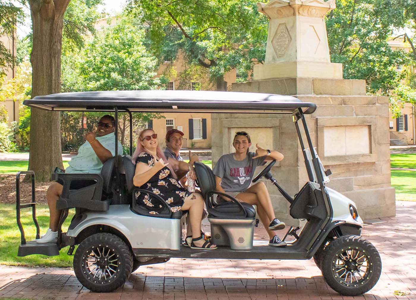 Students with disabilities pose in a parked golf cart by the Maxcy monument.