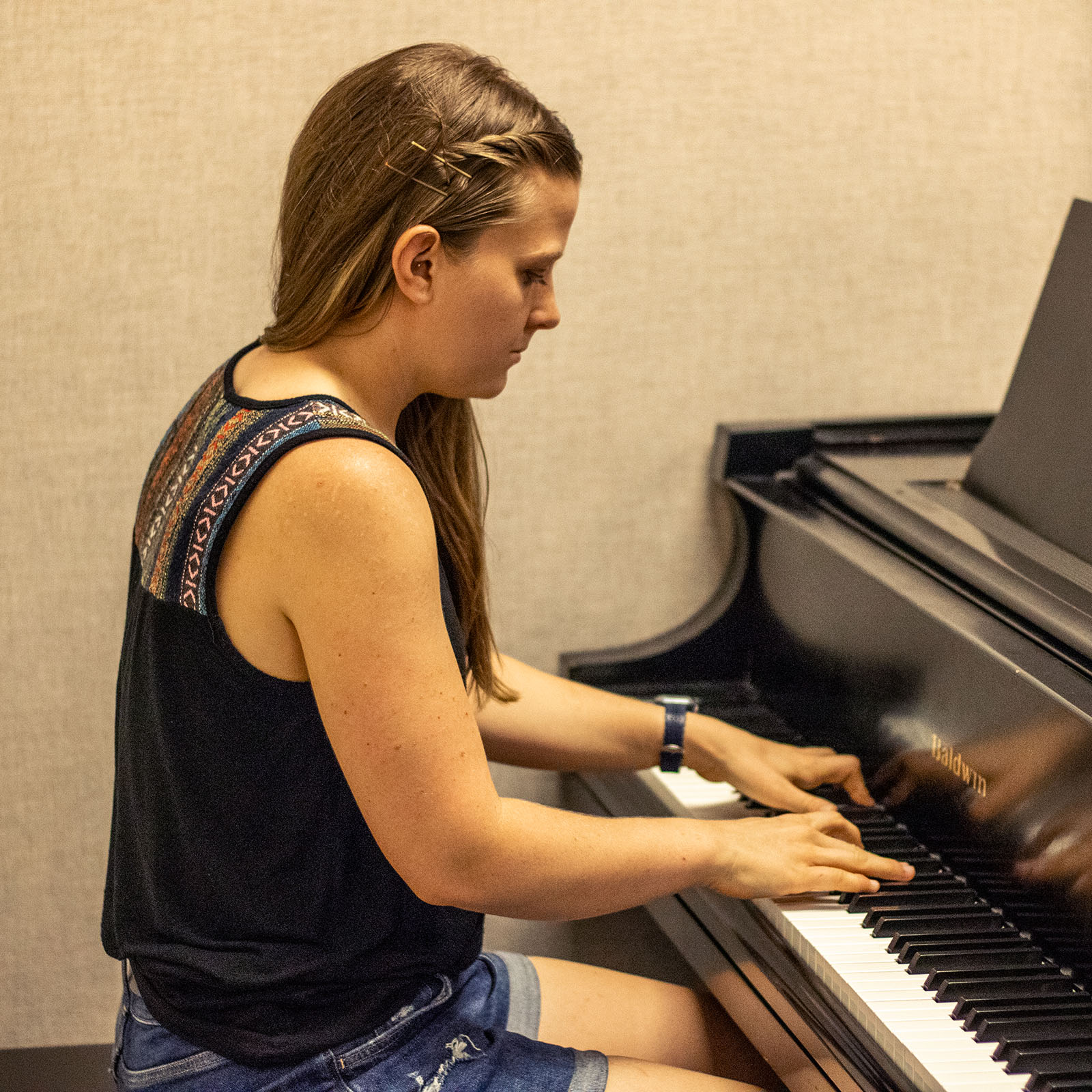 A female student focuses on playing the piano.