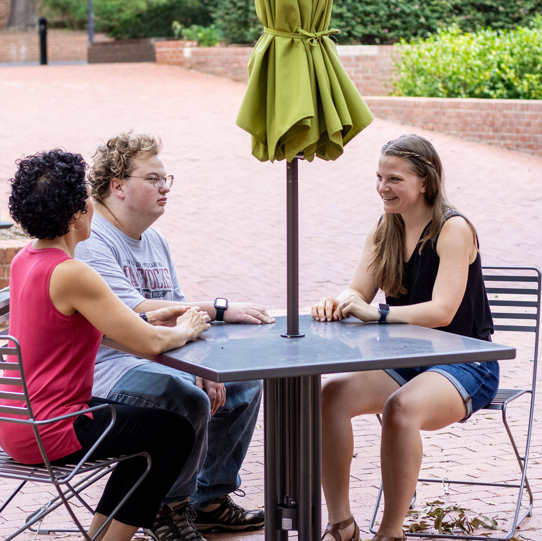 Three students with disabilities chat at a table outside Russell House.
