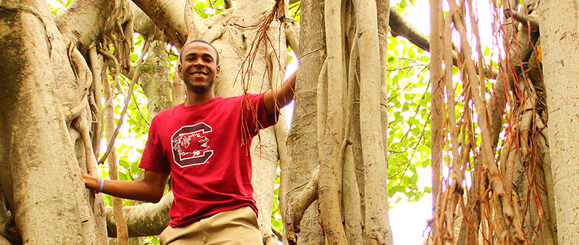 boy wearing a UofSC shirt, in a tree in Australia