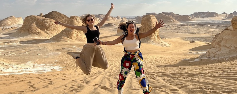two students jumping and smiling in the desert in Egypt