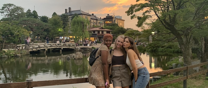 photo of three students posing in front of a river