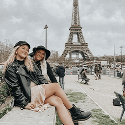 two students sit in front of the Eiffel Tower in Paris, France