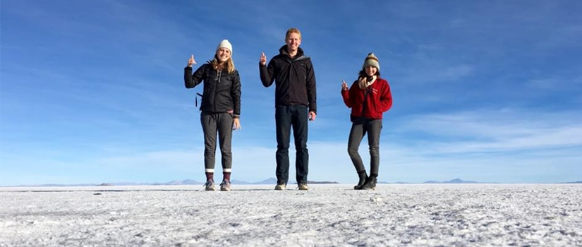 Three students stand on a glacial formation
