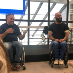 Two men in wheelchairs talk to a group of people