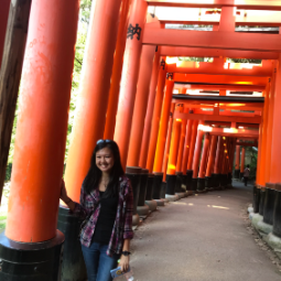 Asian girl stands next to red monument 
