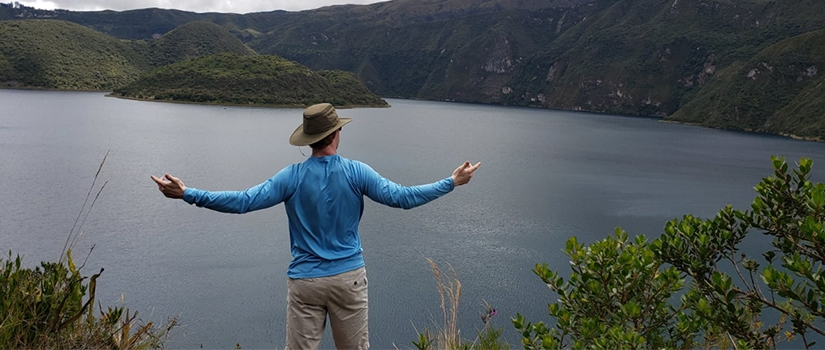 Man with a hat poses in front of a lake