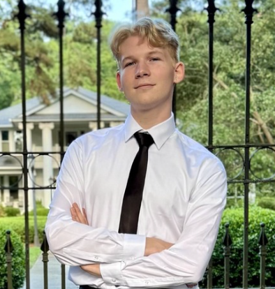 dylan, standing in front of a fence with greenery