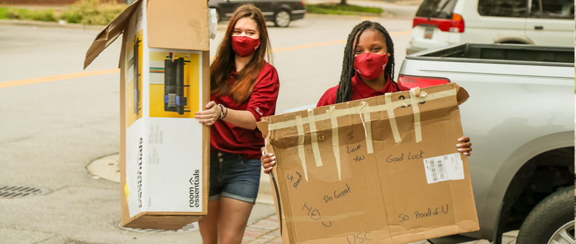 Resident Mentors assist guest by carrying two large boxes during Move-In