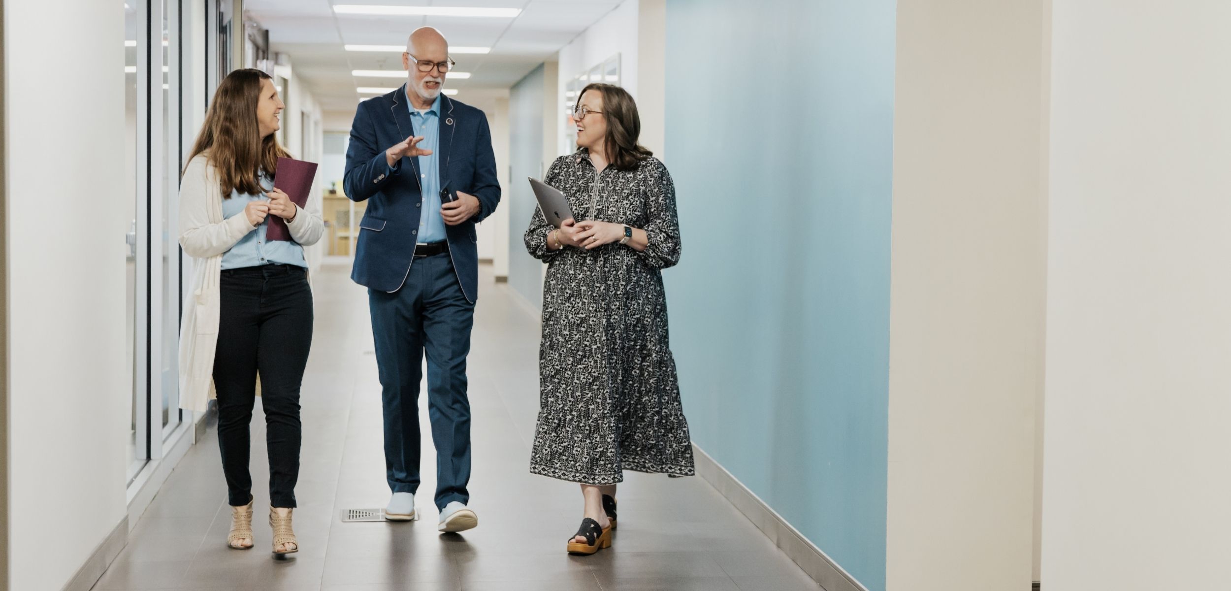 male and two women walking and talking in the hall