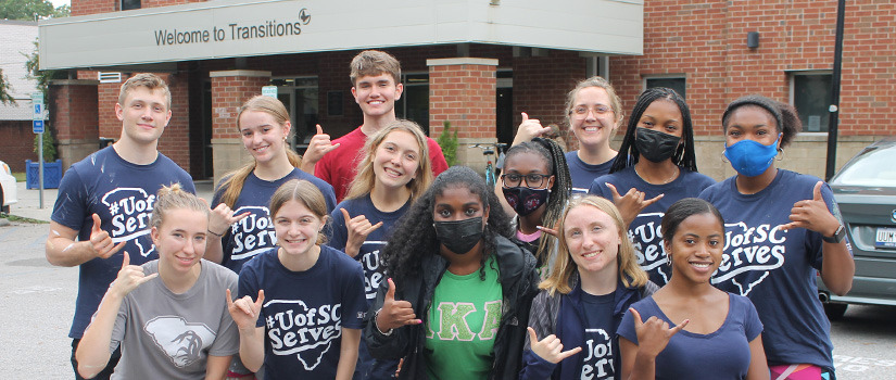 A group of students pose outside of Transitions Homeless Center after a long day of work during an Alternative Break trip.