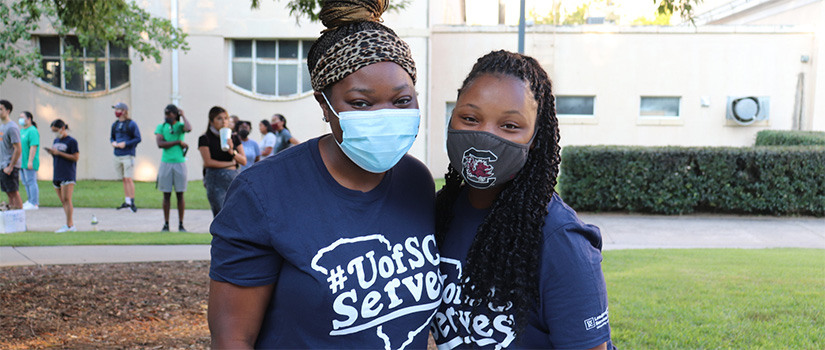 Two female students wearing blue #UofSCServes shirts