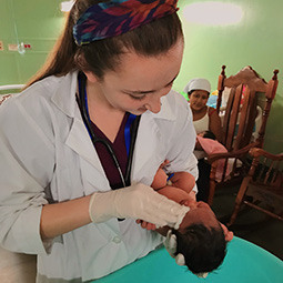 A student holds a baby during clinical work on a service mission trip.