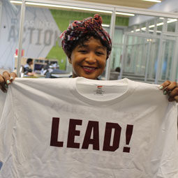 A student displays a T-shirt printed with LEAD.