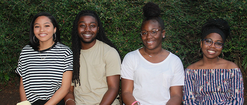 students pose in front of a green background at an OMSA event. 