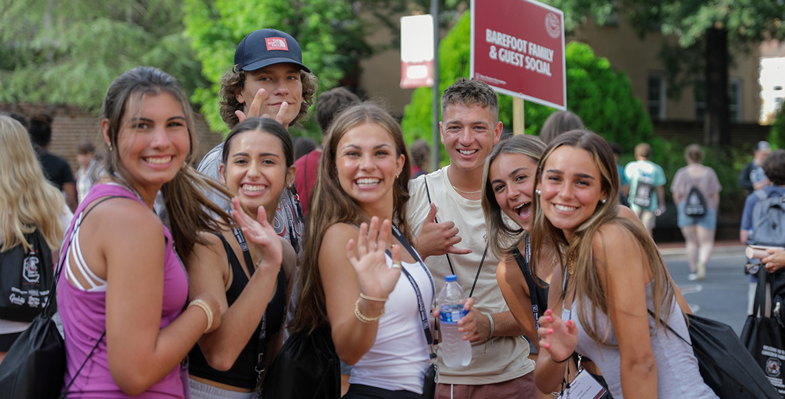 freshman students waving at the camera outside on greene street during orientation