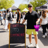 Student stands outdoors beside a chalkboard sign 
