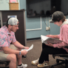 Two students sit at a table indoors and engage in conversation during a campus activity or event.