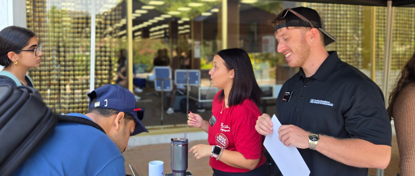 A woman in a red shirt and a man in a black polo  interacting with others.