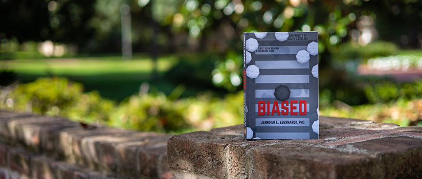 A copy of "Biased" sits on a brick wall.