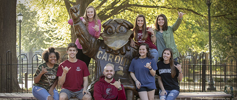 students posing at Cocky statue