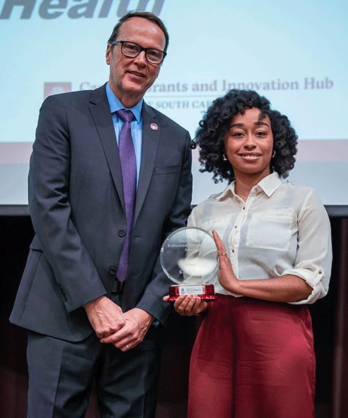 Julius Fridriksson and Kia Zellars pose while Zellars displays her Excellence in Professional Research Staff Award.