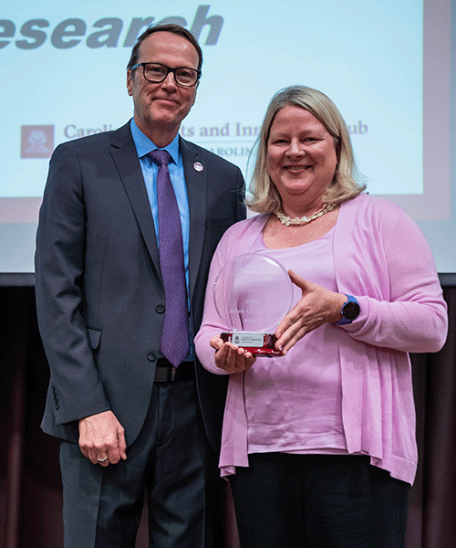 Julius Fridriksson and Lauren Clark pose while Clark displays her Leadership in Research Administration Award.