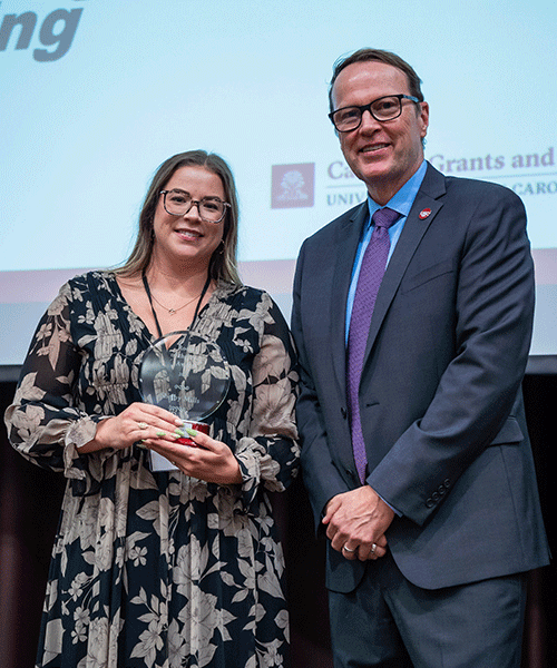 Shelby Mills and Julius Fridriksson pose as Mills displays her Rookie of the Year award.